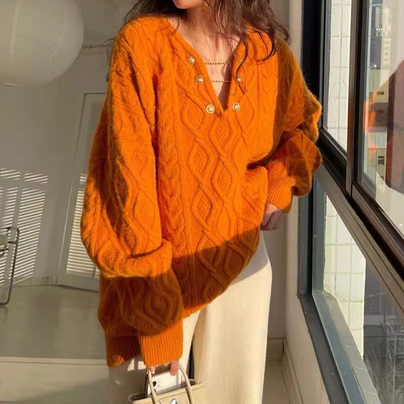 Person wearing an orange cable knit sweater in a room with large windows.