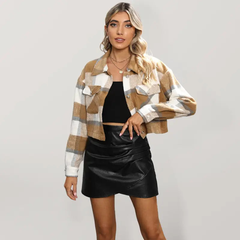 Woman wearing a plaid jacket and black leather skirt on a plain background